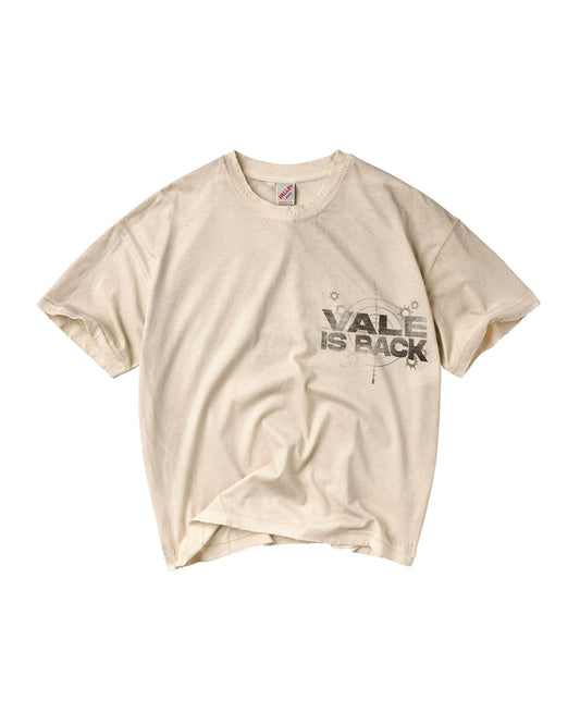 A cream-colored short-sleeve t-shirt with a distressed black graphic on the left chest that reads 'VALE IS BACK' with a compass design.